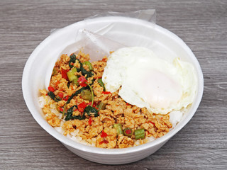 Stir fried minced pork with fried egg on rice in takeout food box for lunch. Thailand street food. 