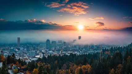 Portland downtown with rolling fog and autumn foliage in shining sunrise and colorful clouds