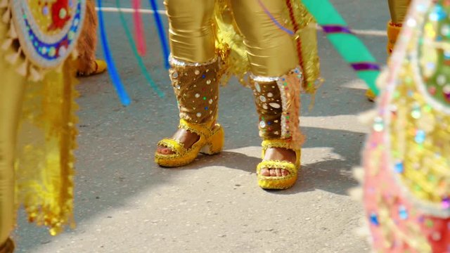 Carnival dancer feet and legs marching on parade route, slow motion