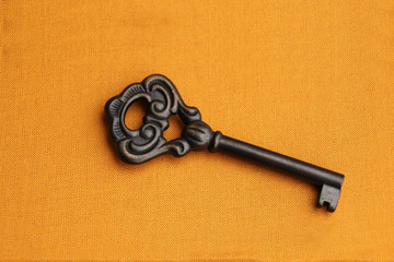 metal vintage beautiful key with twisted patterns on a yellow background, concept of answer, clue,...