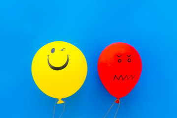 Treat depression concept. Balloons with frustrated and smiling faces on blue background top view