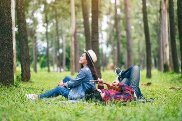 A young couple playing ukulele while sitting and lying down in the woods together