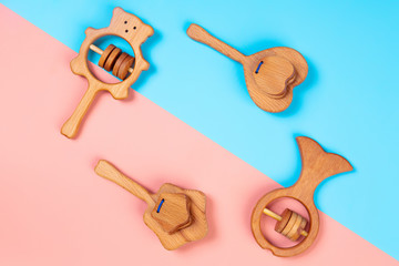 Multi-colored flat lay with eco-friendly wooden toys, rattles in the form of a heart, fish, stars,...
