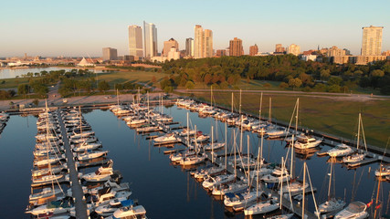 Obraz premium Aerial view of american city at dawn. High-rise buildings, sailing yachts, boat dock. Sunny morning, summer. Milwaukee, Wisconsin, United States