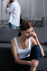 Fototapeta premium crying young woman on sofa and man in white shirt