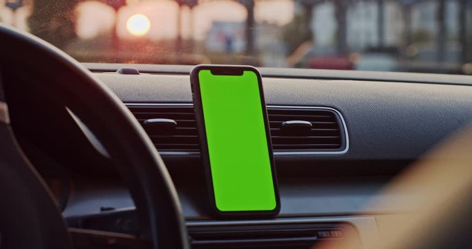 Inside black sports car vertical smartphone mock-up greenscreen device attached to auto dashboard. Close-up. Sunset in background.