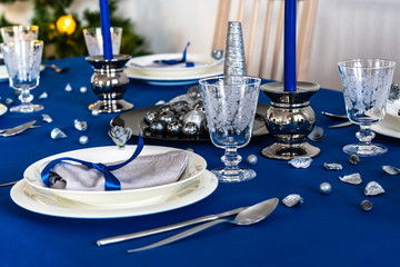 Blue christmas table setting with christmas tree in background