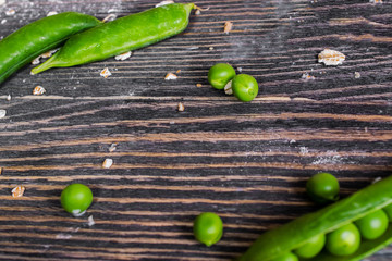 scattered green peas and pods on a wooden table