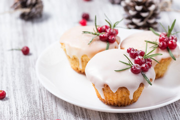 Christmas cupcakes with sugar icing, cranberries and rosemary