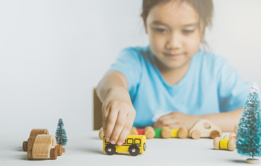 Asian girl playing wooden toys, car, school bus. 