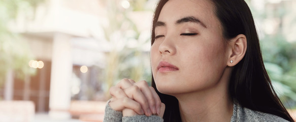Young Asian woman praying with eyes closed