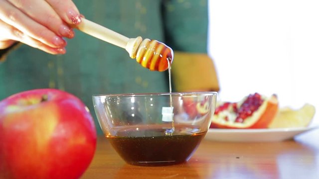 A female hand takes a stick with honey and checks the density for the holiday of Rosh Auchan