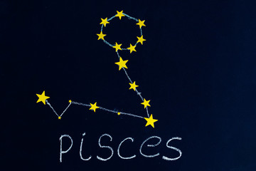 constellation Pisces drawn in chalk and gold stars on a chalkboard looking like a night starry sky