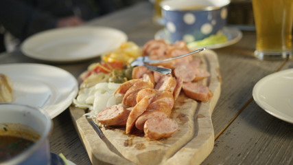 CLOSE UP: Delicious sausages and healthy vegetables sit on wooden cutting board.