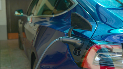CLOSE UP: Charger is plugged into a modern electric car with an empty battery. © helivideo