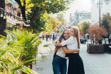 Happy brightful positive moments of two stylish girls hugging on street in city. Closeup portrait funny joyful attarctive young girls having fun, smiling, lovely moments, best friends.