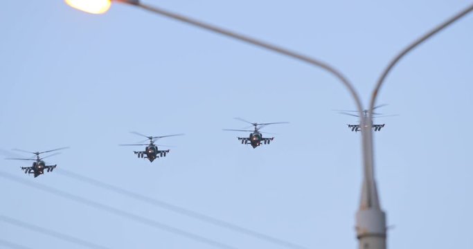 Military parade. War machine in the city. Slow-motion video. 4K UHD slow motion video footage 60 fps. Military helicopter on battlefield flies overhead passing in blue skies and clouds at city.