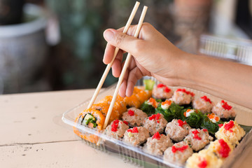 Mix japanese sushi rolls in take away package.