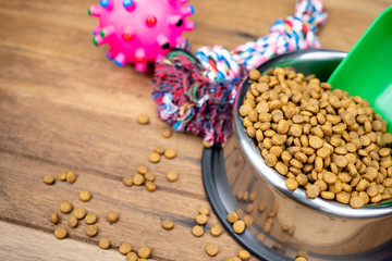 Dry food in stainless bowls on wooden table.  Pet supplies concept
