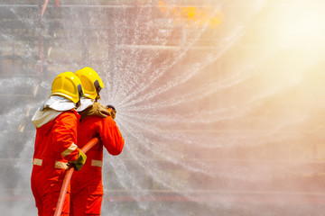 Two brave firefighter using extinguisher and water from hose for fire fighting, Firefighter...