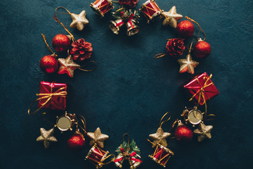 Winter holidays. Flat lay of abstract Christmas wreath frame from ornaments on dark teal blue background. Copy space. © golubovy