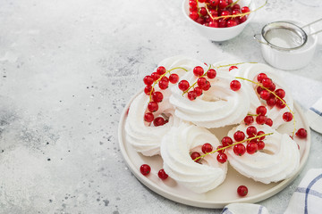 Fototapeta na wymiar White meringue. Meringues in the form of rings with bunches of red currants on a white plate