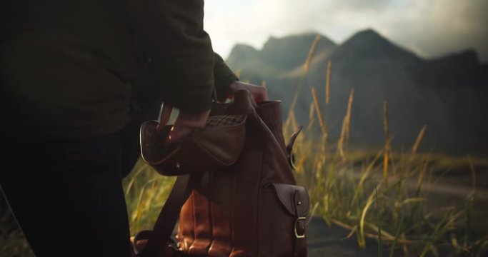 Photographer / Hiker takes his camera out of brown backpack