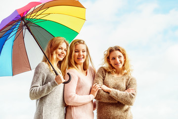 Three women under colorful umbrella
