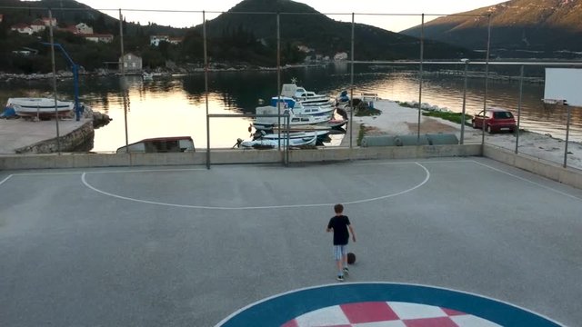 A Boy playing Soccer on a Pitch in Croatia near the Seside