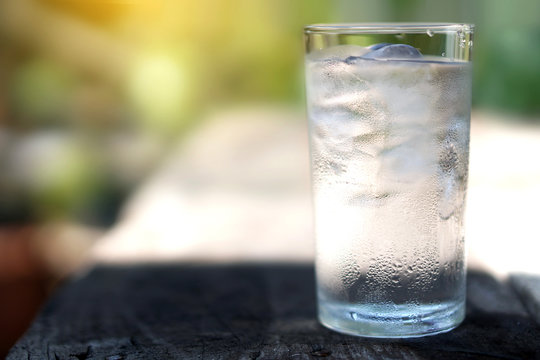 a glass of water with ice on nature background