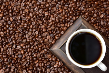 Cup of hot coffee on coffee beans