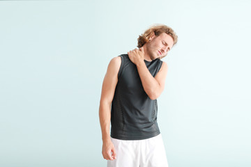Young man suffering from pain in neck on color background