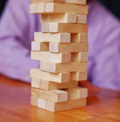 Stacks of block wood game on a wooden table with player in the background.
