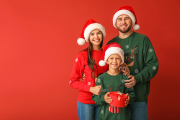 Fototapeta premium Happy family in Christmas sweaters and Santa hats on color background
