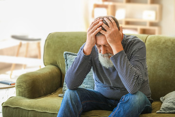 Senior man suffering from headache at home