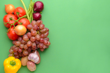 Many healthy vegetables with grapes on color background