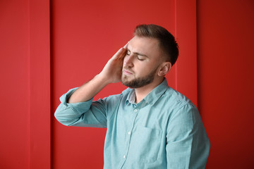 Young man suffering from headache on color background