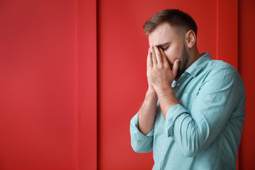 Young man suffering from headache on color background