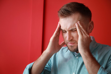 Young man suffering from headache on color background
