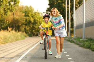 Mother teaching her son to ride bicycle outdoors