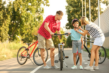 Parents teaching their son to ride bicycle outdoors