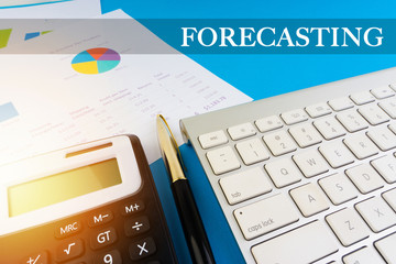 Flat lay view of office workspace with keyboard, pen, paperwork and words FORECASTING. Business concept
