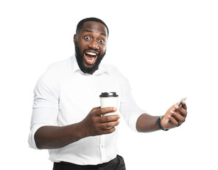 Excited African-American businessman with cup of coffee and mobile phone on white background