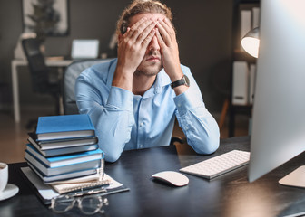 Tired man trying to meet deadline in office