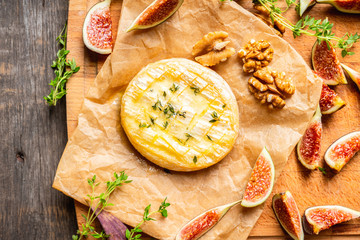 Baked camembert cheese with figs, walnuts, honey and thyme on the rustc background. Selective focus. Shallow depth of field.