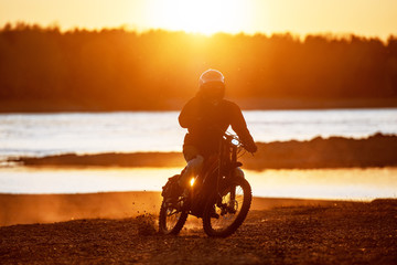 Motorcyclist on electric enduro motorbike in sunset light
