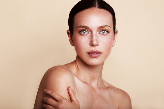 Beauty woman portrait with nude makeup shooted on a beige background