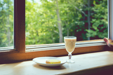 Tea with milk and spices on the background of an open window with mountain views