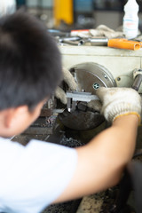 Metal worker turner operating lathe machine at industrial manufacturing factory