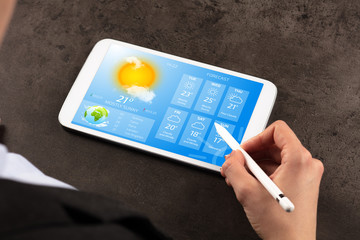Business woman checking weekly weather forecast on tablet